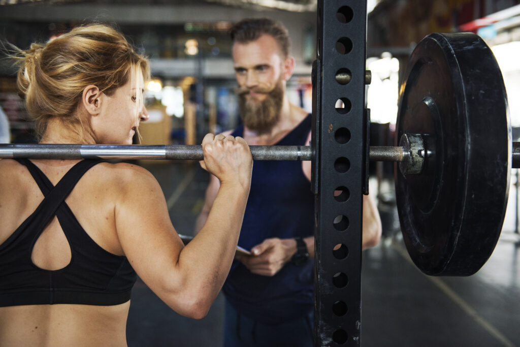 Donna che fa squat con personal trainer